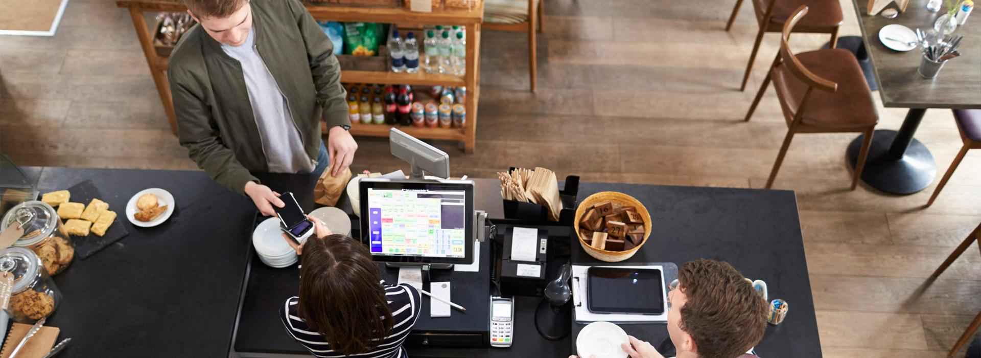 man at counter making purchase at coffee shop