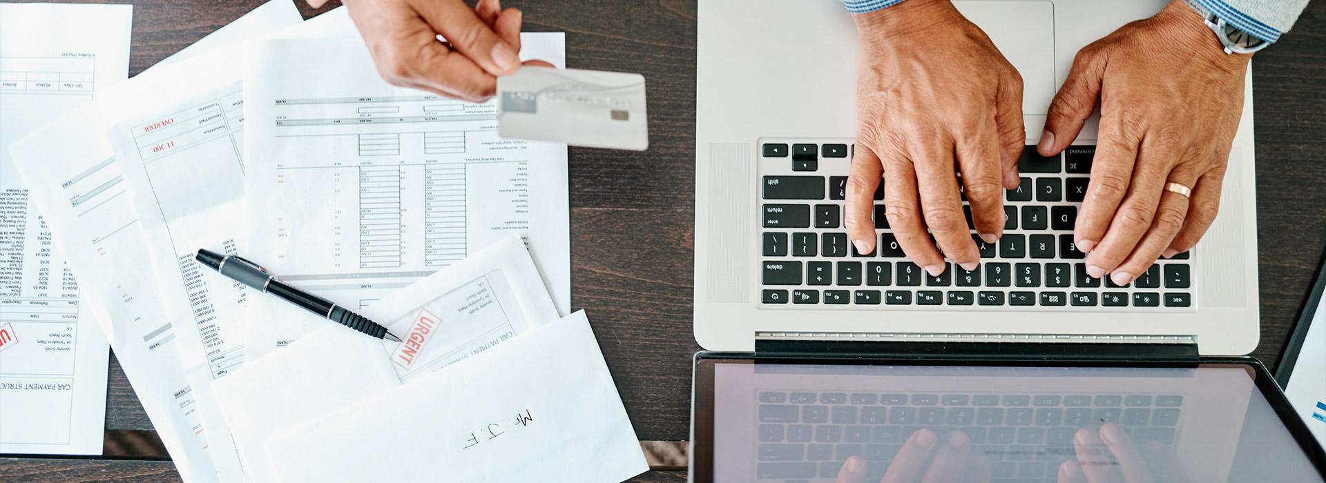 Important papers and a hand typing on a laptop